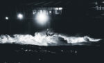 Black and white fine art photographs of surfers in action and at rest, silhouetted against bright skies and dramatic waves, capturing the essence of surfing in a minimalist, high-contrast visual style.