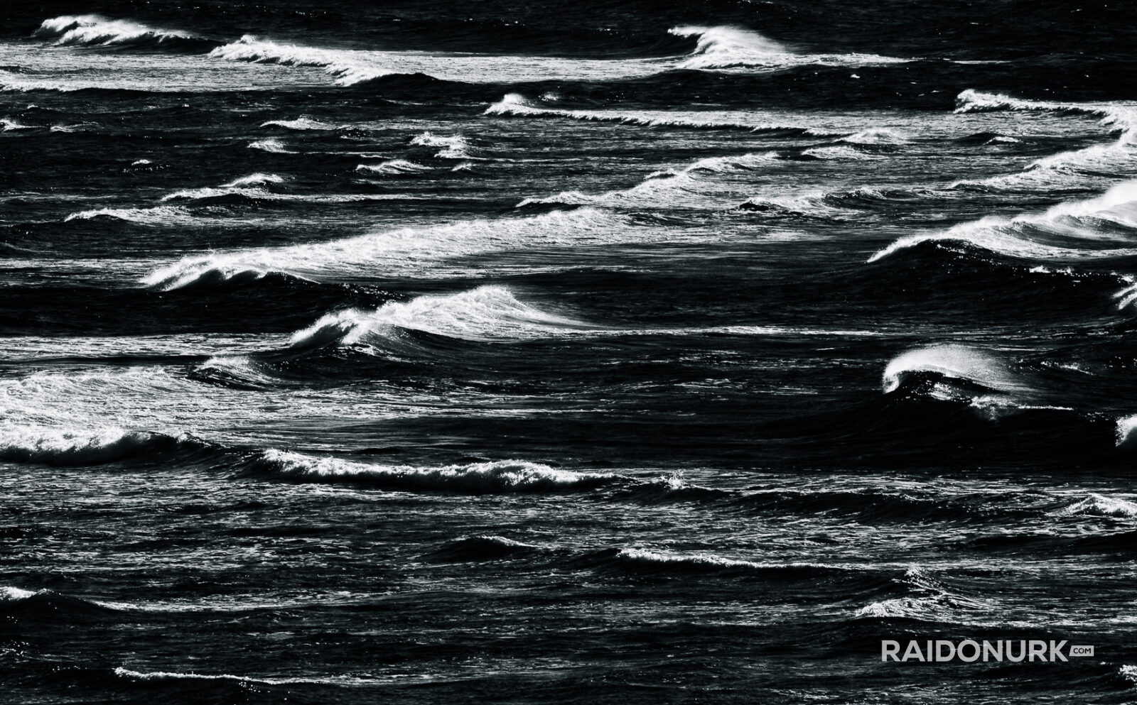 Black and white fine art photographs of surfers in action and at rest, silhouetted against bright skies and dramatic waves, capturing the essence of surfing in a minimalist, high-contrast visual style.