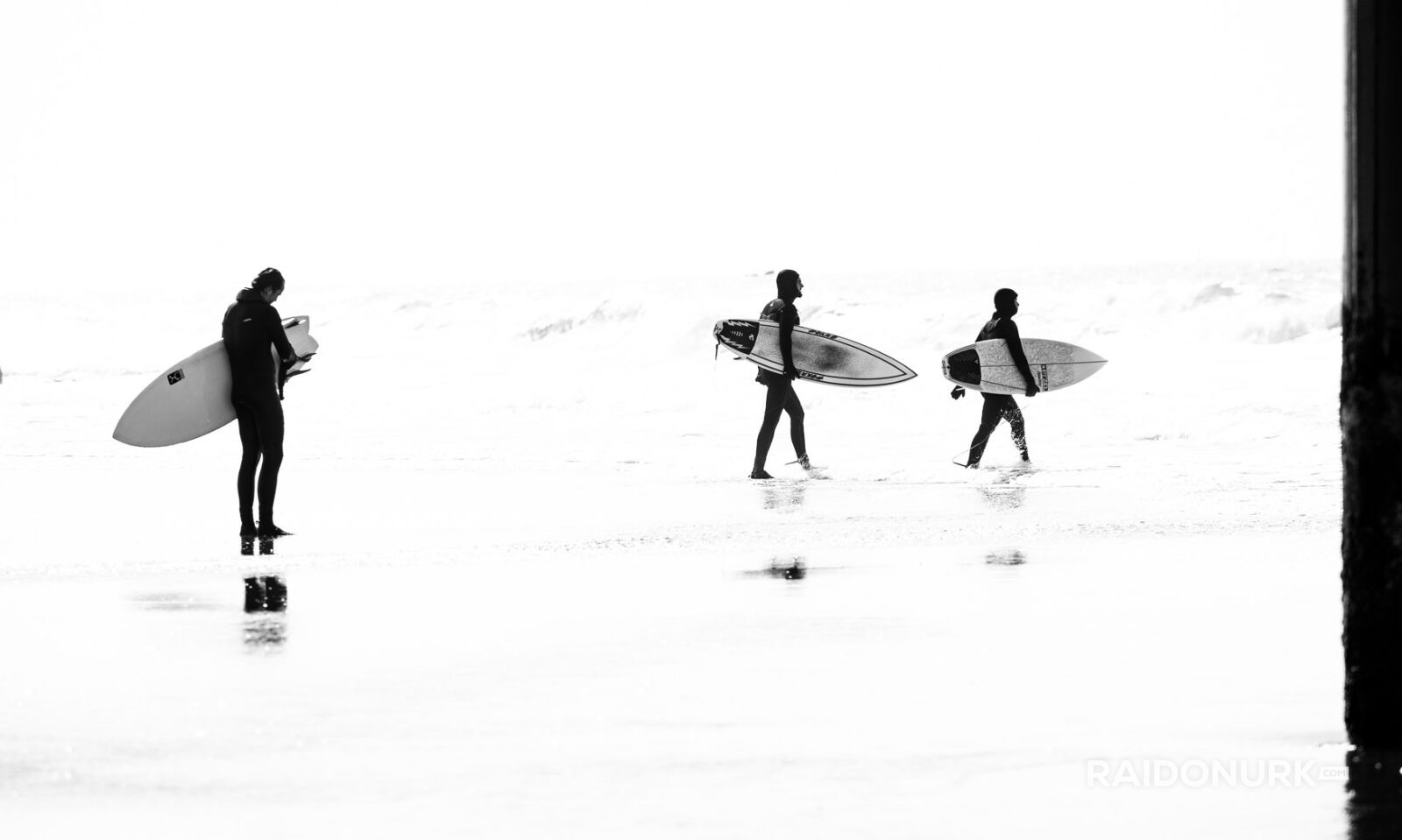 Black and white fine art photographs of surfers in action and at rest, silhouetted against bright skies and dramatic waves, capturing the essence of surfing in a minimalist, high-contrast visual style.