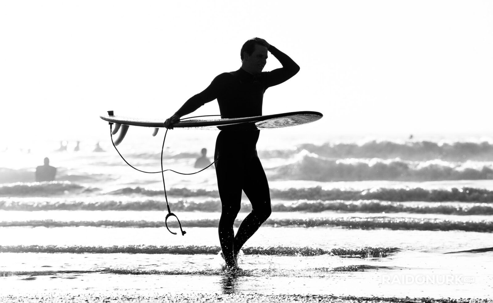 Black and white fine art photographs of surfers in action and at rest, silhouetted against bright skies and dramatic waves, capturing the essence of surfing in a minimalist, high-contrast visual style.