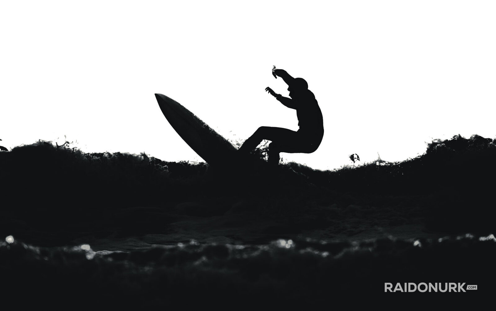 Black and white fine art photographs of surfers in action and at rest, silhouetted against bright skies and dramatic waves, capturing the essence of surfing in a minimalist, high-contrast visual style.