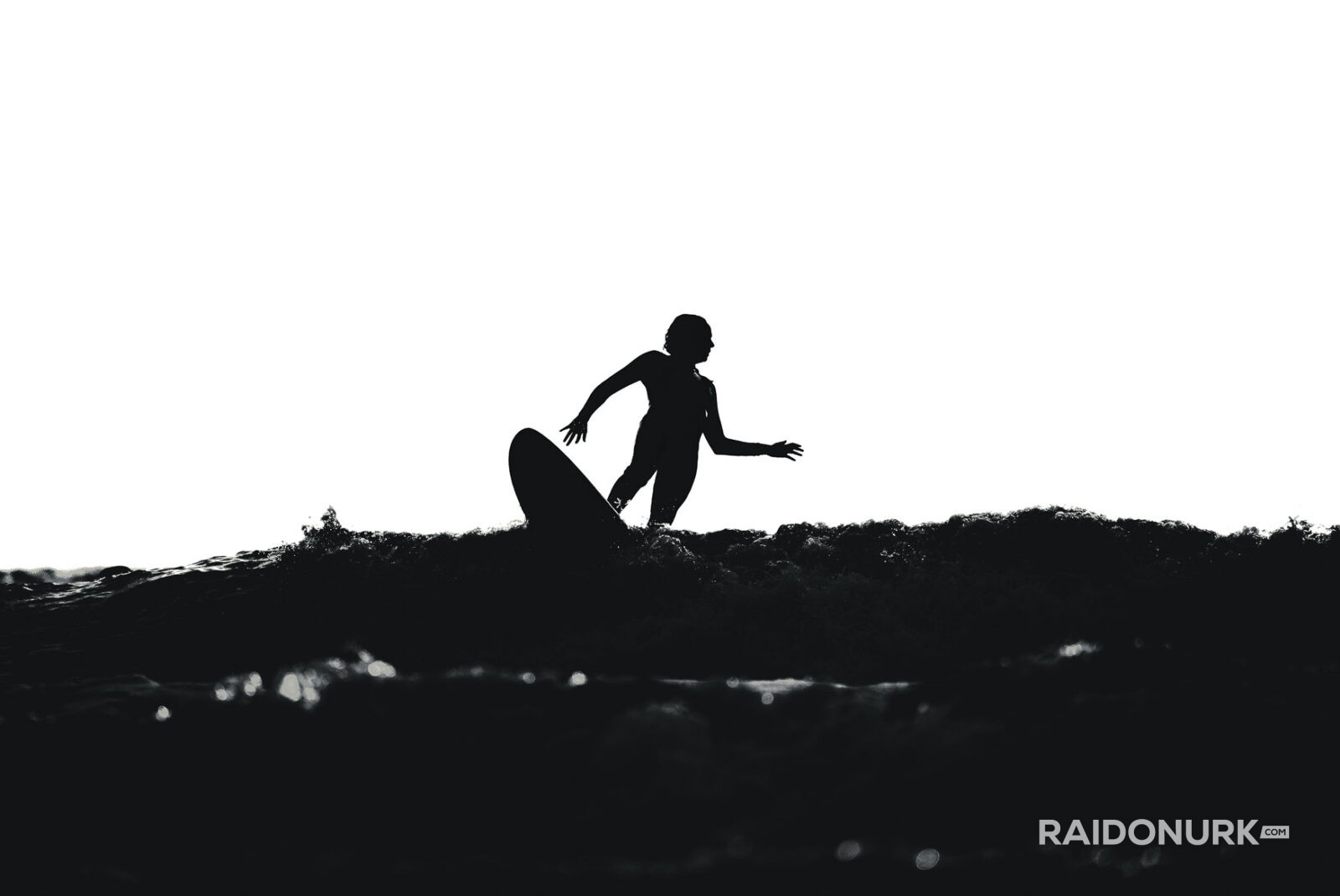Black and white fine art photographs of surfers in action and at rest, silhouetted against bright skies and dramatic waves, capturing the essence of surfing in a minimalist, high-contrast visual style.